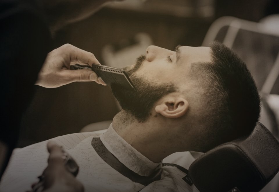Site da Barbearia Besegatto, com fundo escuro e detalhes dourados, exibindo o atendimento na cadeira